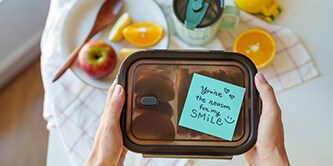 Eine Lunchbox mit einer herzlichen Botschaft auf einer Post-it® Haftnotiz: „Du bist der Grund für mein Lächeln“
